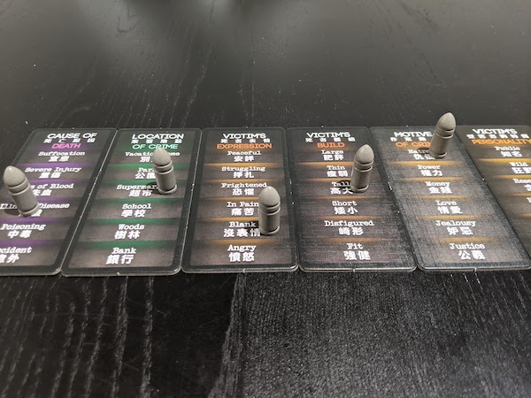 Mid game of Deception Murder in Hong Kong, six scene tiles laid out with clues given by the scientist. Including Victim's expression, build, and personality.